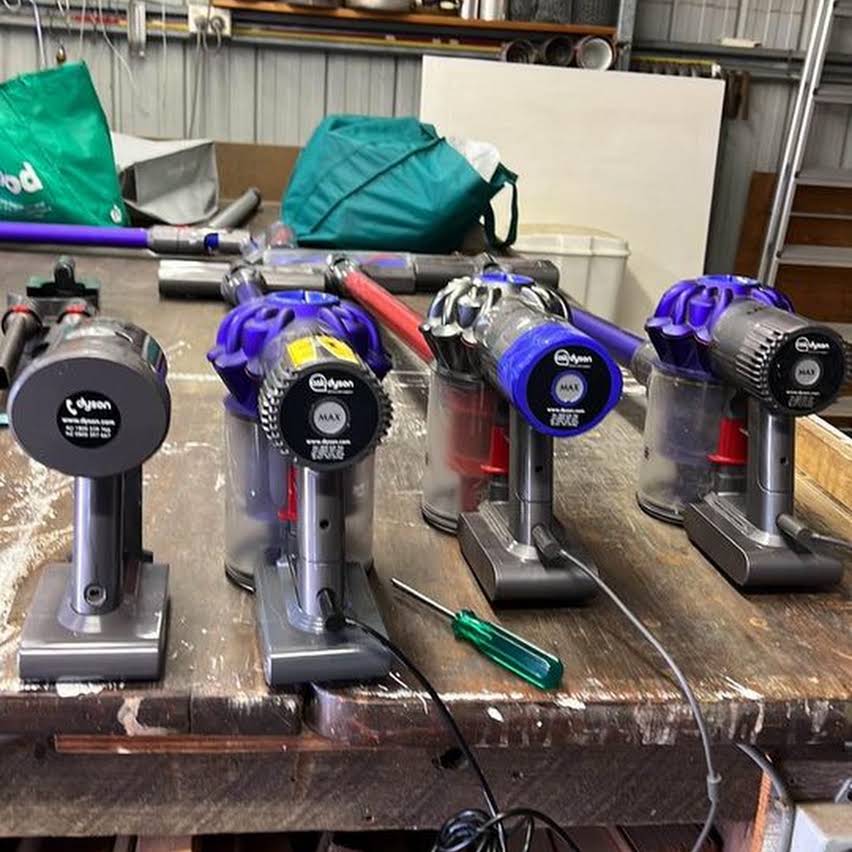Four Dyson stick vacuums being repaired on Eddie's workbench